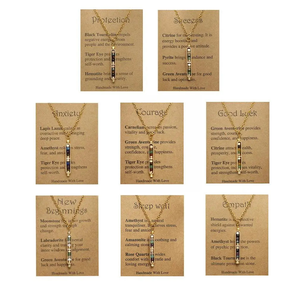 Collection of handmade crystal pendant necklaces with labels for protection, success, anxiety, courage, luck, new beginnings, sleep well, and empathy.