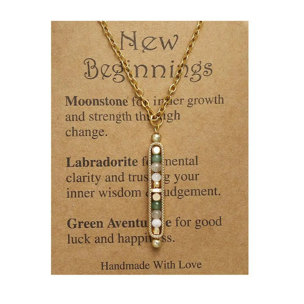 Light luxury gold pendant necklace with natural stones on a card titled 'New Beginnings', featuring moonstone and labradorite.