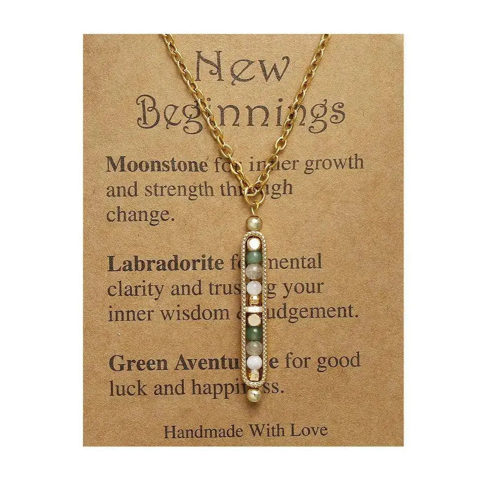 Light luxury gold pendant necklace with natural stones on a card titled 'New Beginnings', featuring moonstone and labradorite.