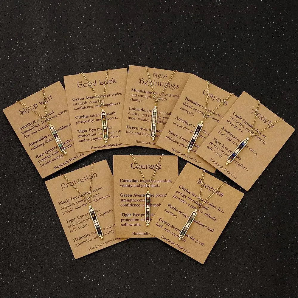Collection of inspirational pendant necklaces displayed on kraft paper cards with meanings and crystals.